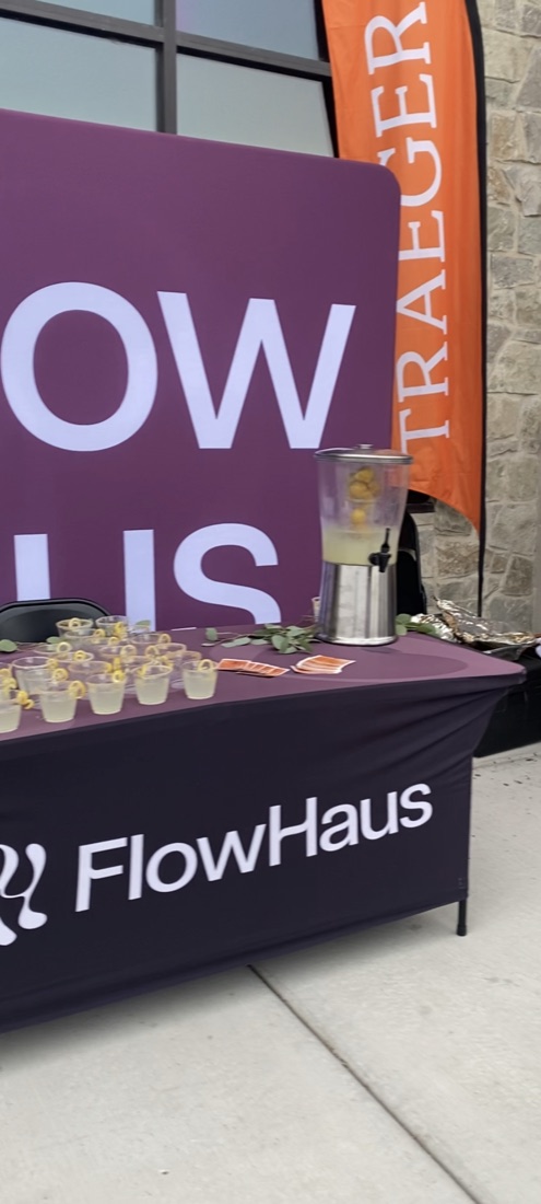 FlowHaus event table with a Traeger banner behind it